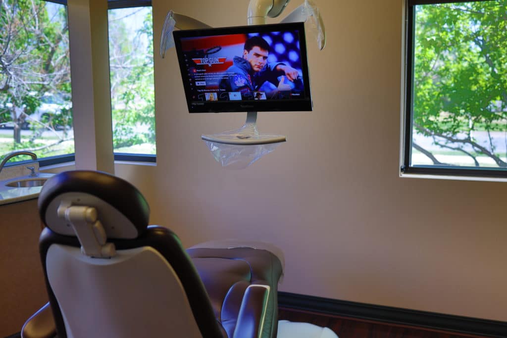 Entertainment Comfortable dental treatment room with patient chair and mounted television for entertainment during appointments